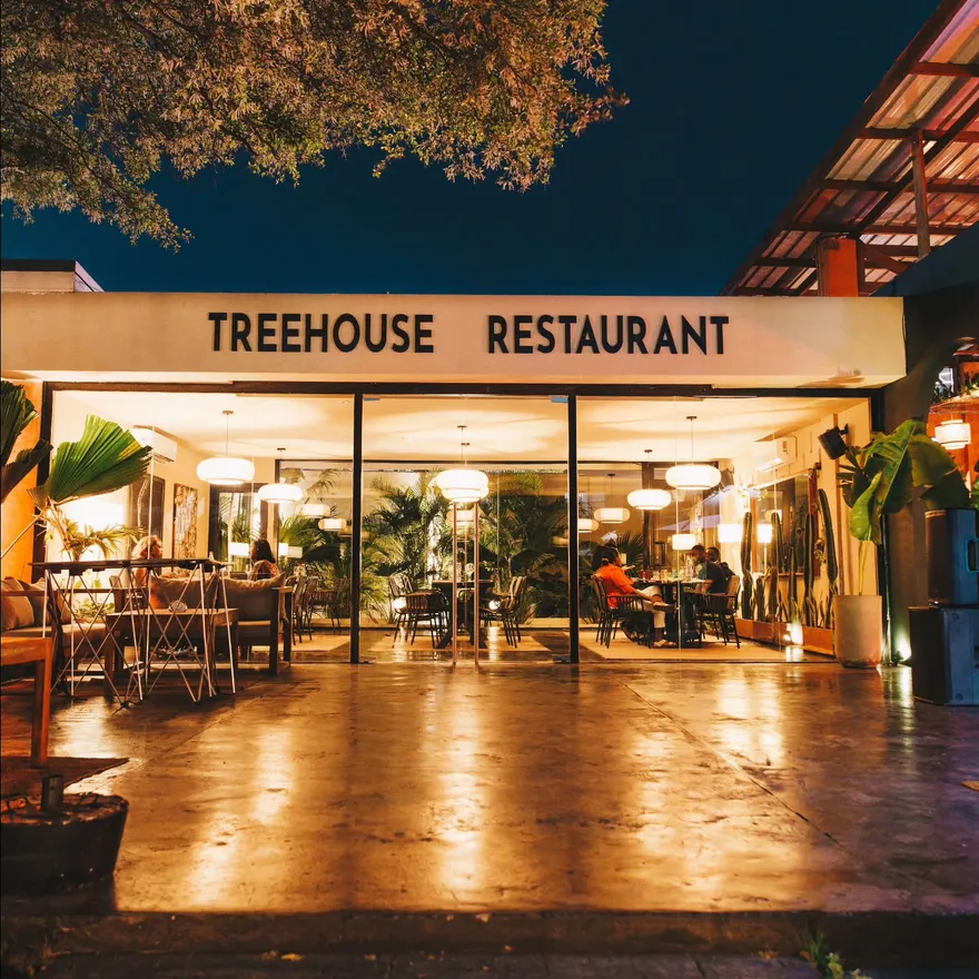 The Treehouse Restaurant entrance at night, sign lit above the glass