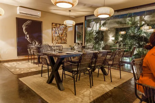 The inside room — rattan pendants, African art, palms behind glass